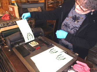 Deborah Holcomb pulls the first proof of
                her wood engraving - on the smaller Showcard/Vandercook
                sign/proof press